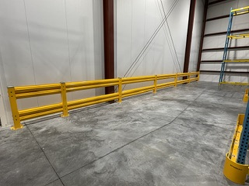 Yellow safety guardrail along warehouse wall